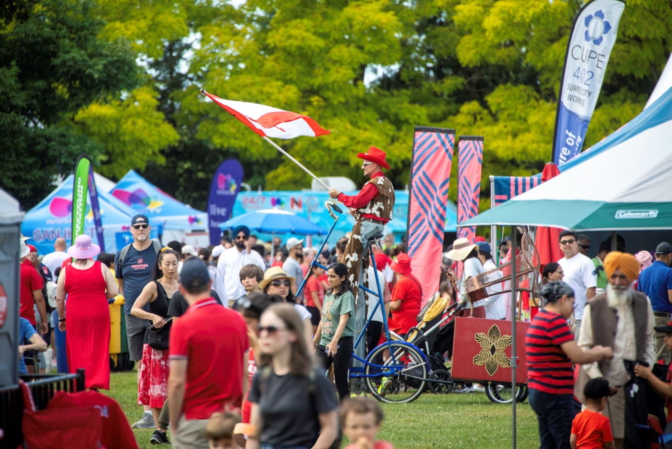 A person on a unicycle waving a Canadian flag.