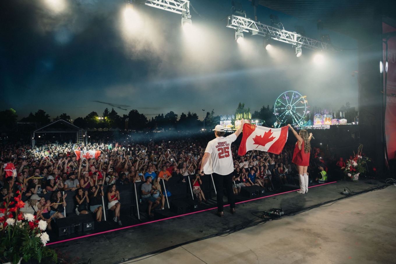 The Reklaws holding a Canadian flag on stage in front of a crowd.